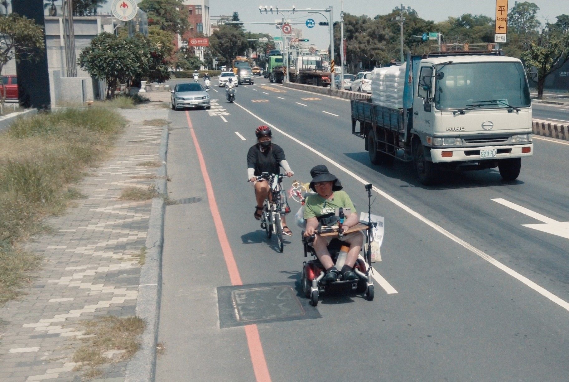 人行道長雜草或是堆滿雜物，小齊只好冒險走到車道上，與車同行